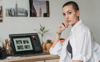 thoughtful woman with stylus working with photos on laptop