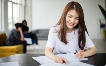positive asian woman with notebook studying in classroom