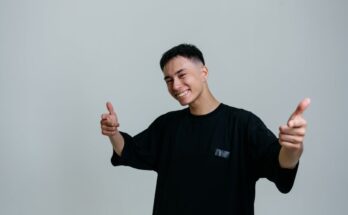 man in a black crew neck shirt pointing his fingers at the camera