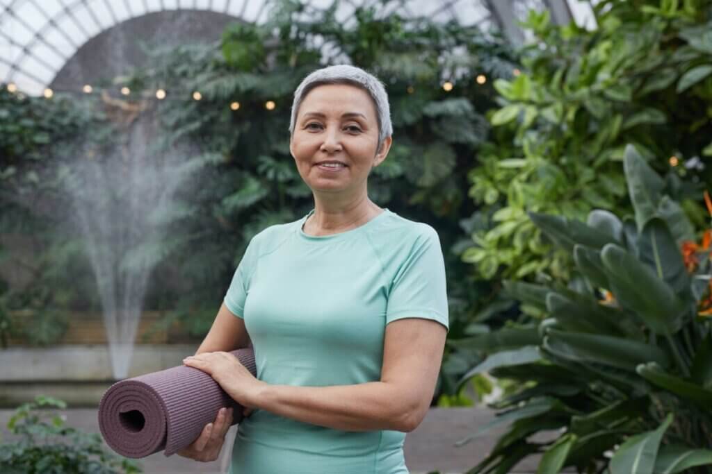 woman smiling while holding a yoga mat