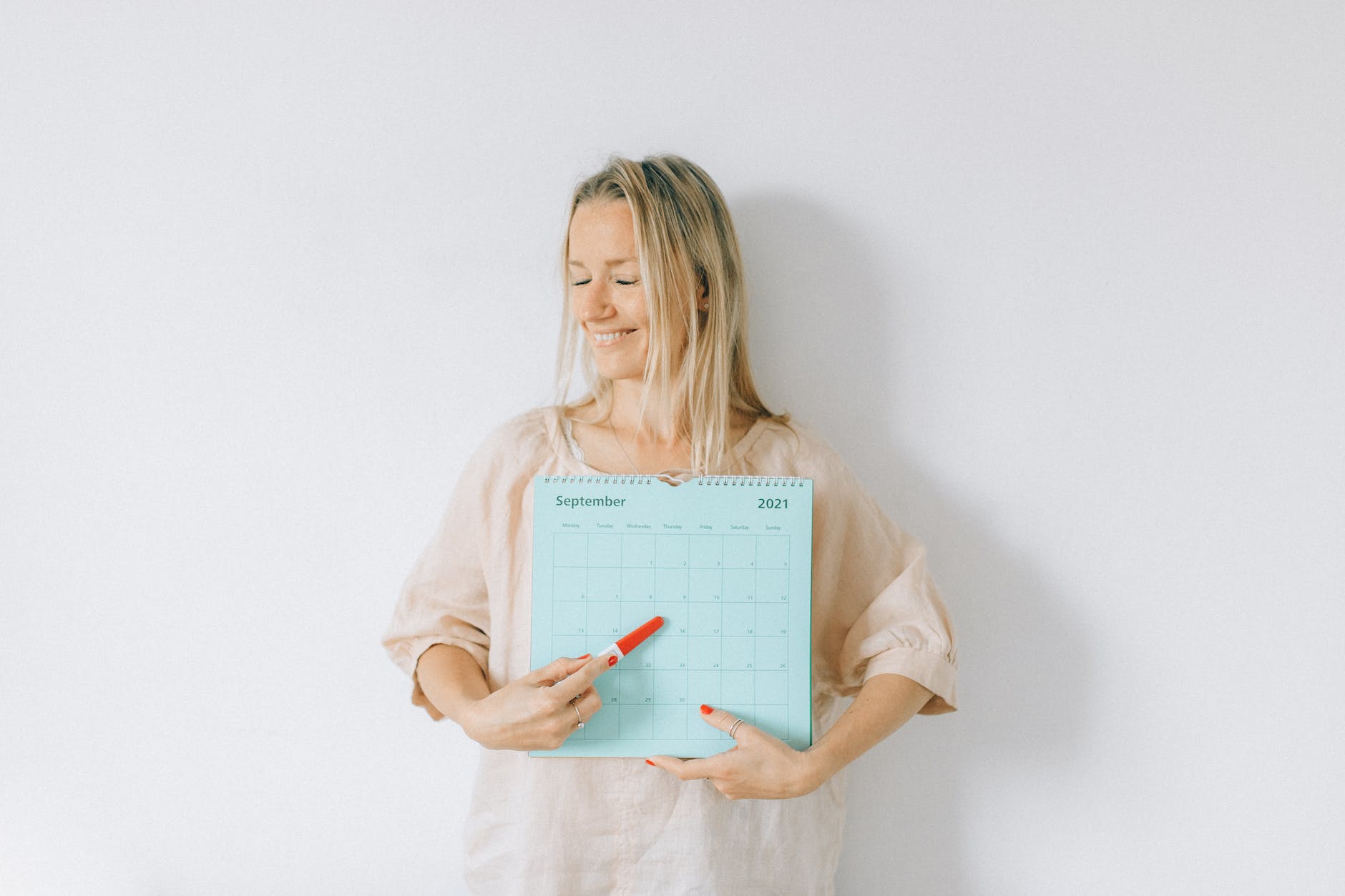 a woman pointing a pregnancy test at a calendar