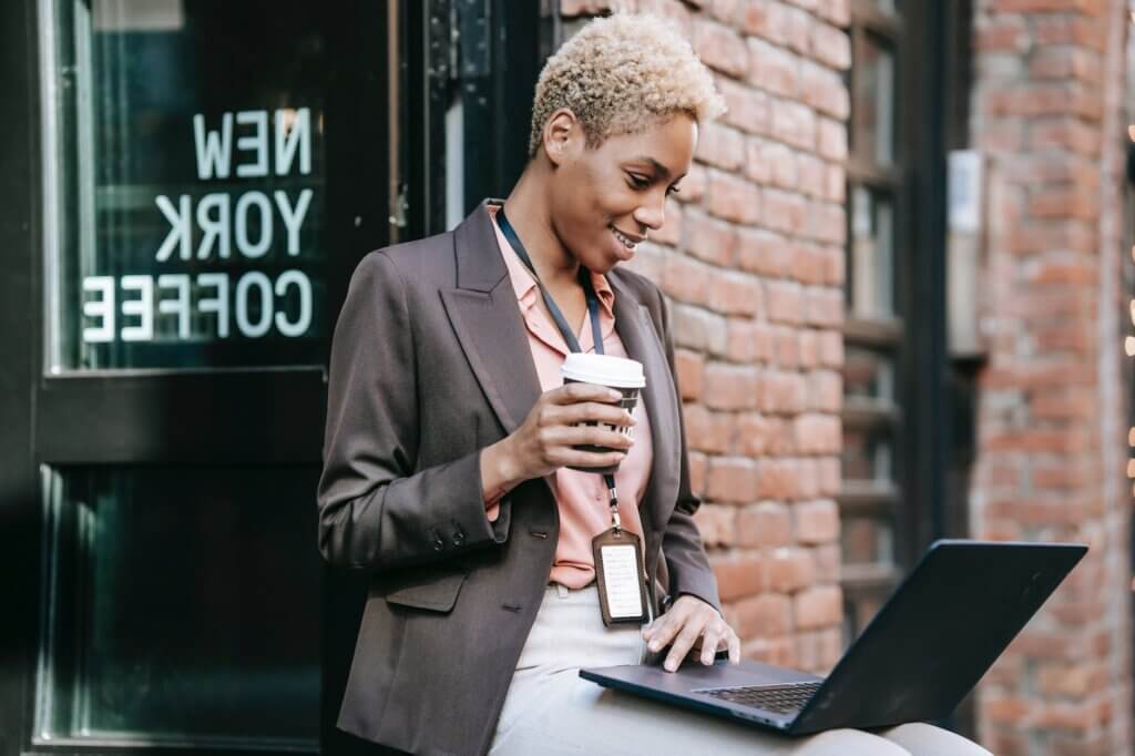 smiling black entrepreneur watching laptop during coffee break